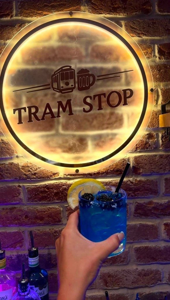 Signature cocktail beside the Tram Stop neon sign